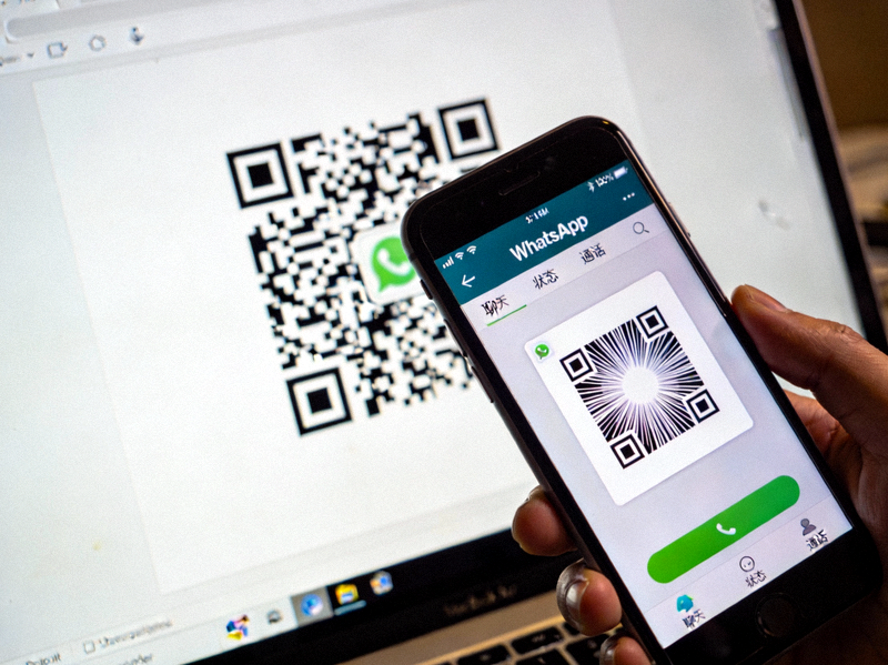 手机屏幕显示WhatsApp应用界面正在扫描电脑屏幕上的二维码